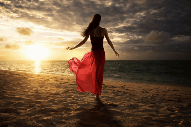Woman in red, sunset beach stroll.
