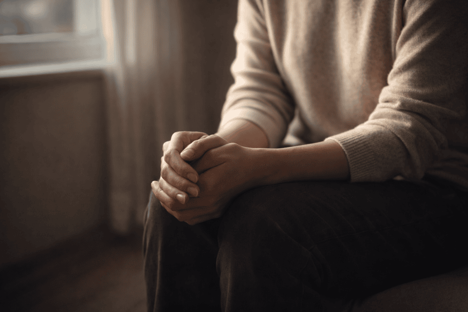 Person sitting with hands clasped indoors
