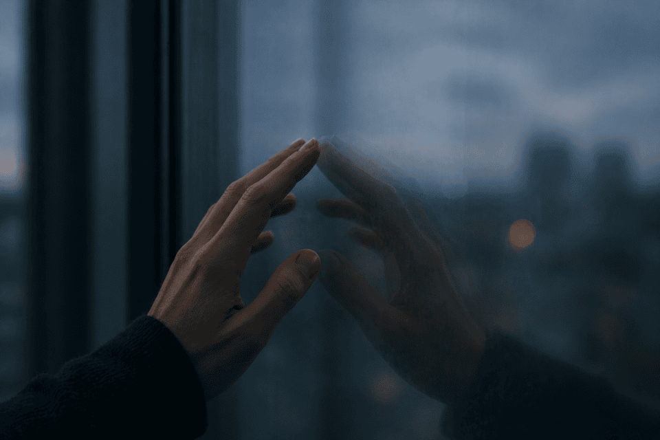 hand resting on glass with slightly offset reflection in low light